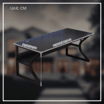 A modern gaming desk setup featuring a sleek, gray desk with a curved black frame. The desk holds a monitor displaying a mountain landscape, a keyboard, a mouse, and various accessories. A gaming PC with blue LED lights is positioned underneath. The wall has a pegboard with a digital clock and other items.